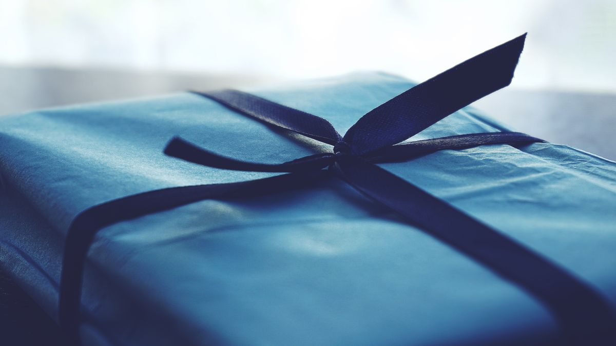 Caja de regalo azul envuelta con cinta, representando una caja de suscripción para fans