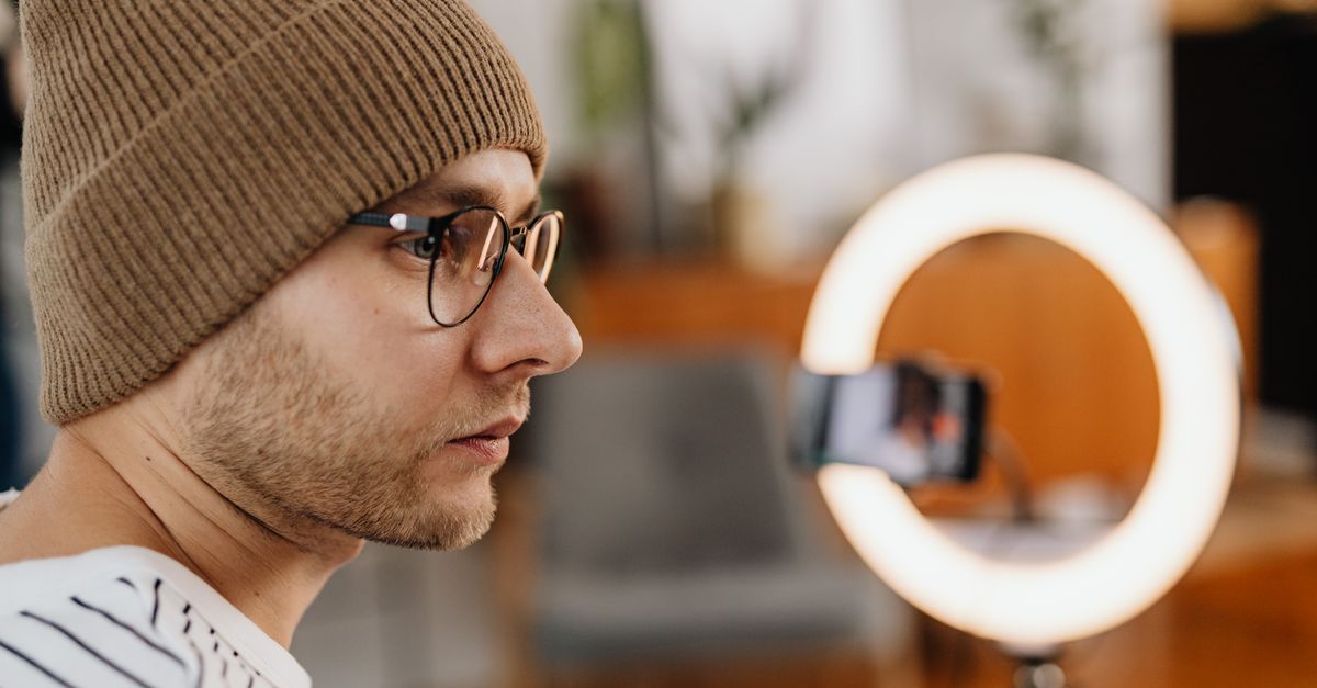 Creador de contenido grabando un video con smartphone y aro de luz en su hogar, representando la economía del creador digital