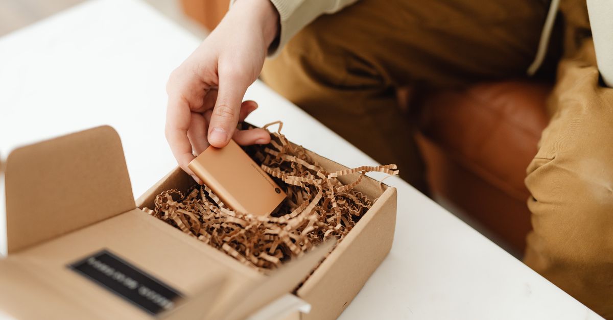 Persona abriendo una caja de cartón con papel de relleno, representando la experiencia de unboxing